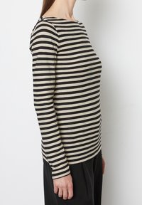 Maglia a maniche lunghe con righe orizzontali nere e beige, scollo rotondo, tessuto di cotone morbido e silhouette aderente.