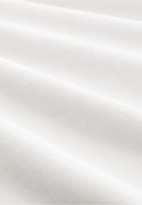 Tela blanca con sutiles pliegues diagonales y una fina textura tejida visible en una suave y uniforme iluminación.