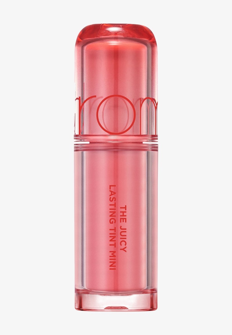 Rosa gjennomsiktig sylinderformet leppefargebeholder merket "The Juicy Lasting Tint Mini" mot en enkel hvit bakgrunn.