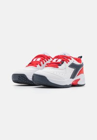 Scarpe da ginnastica bianche con lacci rossi, accenti grigi e una suola in gomma nera texturizzata. Il design include perforazioni per la traspirabilità.
