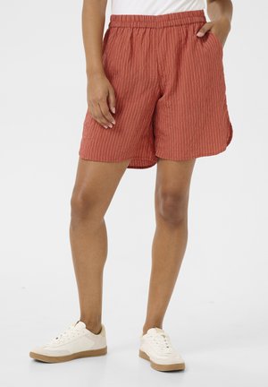 Rustfarbene Shorts mit vertikalen weißen Streifen, ausgestattet mit einem elastischen Bund und seitlichen Taschen, aus leichtem Stoff gefertigt.