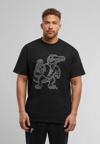 Black cotton t-shirt featuring a large, gray graphic of an alligator with the letter "F" on its torso. Crew neck and short sleeves.