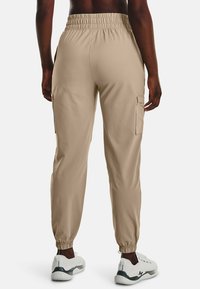 Beige cargo tepláky s elastickým pasem, zúženými manžetami, bočními kapsami a hladkým, lehkým textilním povrchem.