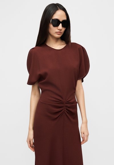 Μπορντό φόρεμα με κοντά φουσκωτά μανίκια, στρογγυλή λαιμόκοψη και ρυθμισμένες λεπτομέρειες στη μέση. Λεπτή υφή με εφαρμοστή σιλουέτα.