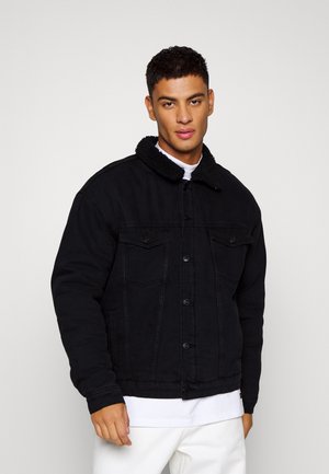 Mustmustest tume denim jope sherpa kraega, kahe rinna tasku ja nööpide sulgemisega. Kangas on sileda tekstuuriga ja veidi kulunud detailidega.