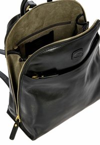 Sac à dos en cuir noir avec une fermeture éclair dorée, un intérieur en daim, plusieurs poches et une forme épurée avec une texture lisse.