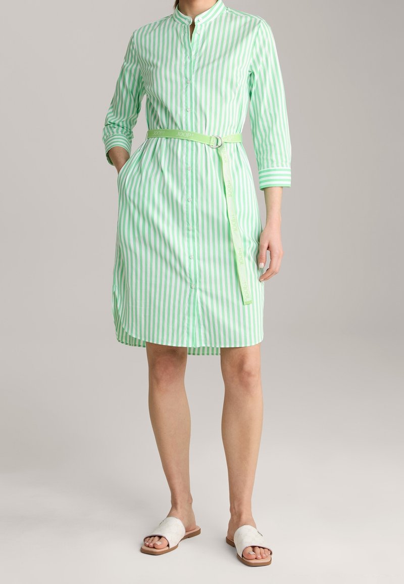 Sukienka koszulowa w zielono-białe paski, zapinana na guziki z kołnierzykiem, rękawy do połowy przedramienia, pasek materiałowy, dwie kieszenie po bokach i lekka bawełniana tkanina.