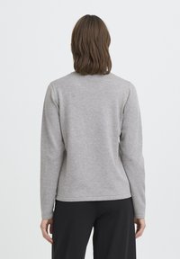 Pull gris à manches longues avec un col rond, une texture lisse et un ourlet droit. Présente un design simple sans motifs ni accessoires visibles.