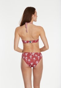 Bikini v rust farbe s bielou potlačou palmového stromu. Top bez ramienok s halter krkom a zapínaním na klips, zodpovedajúce nízko pásové nohavičky. Hladká textúra.
