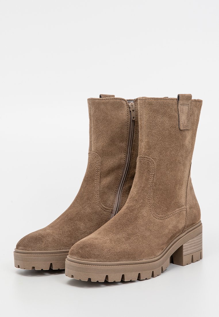 Para brązowych zamszowych botków do połowy łydki z bocznym zamkiem, masywną gumową podeszwą i słupkowym obcasem na białym tle.