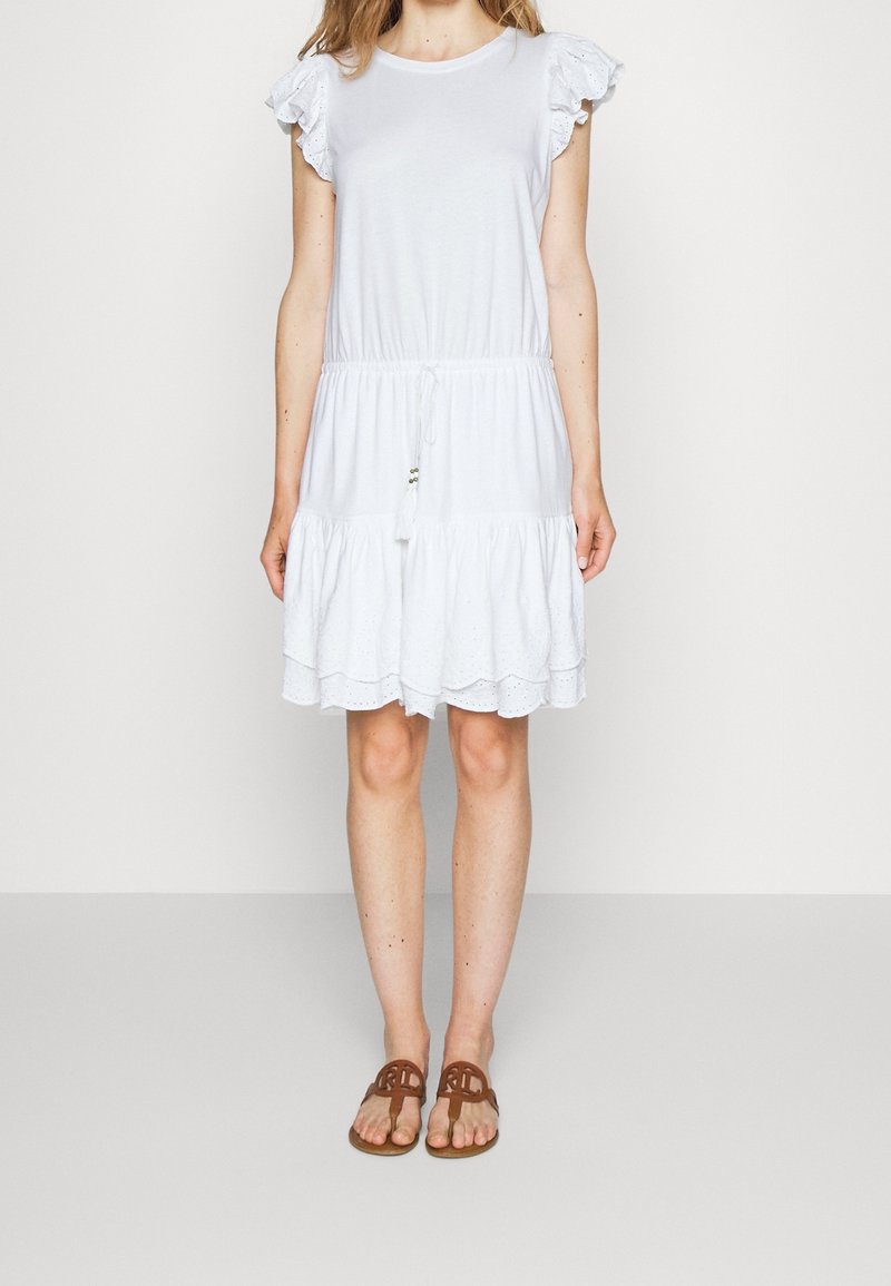 White cotton dress with ruffle sleeves, elastic waist, and tiered skirt. Notable eyelet detailing and tassel accents at the waist.