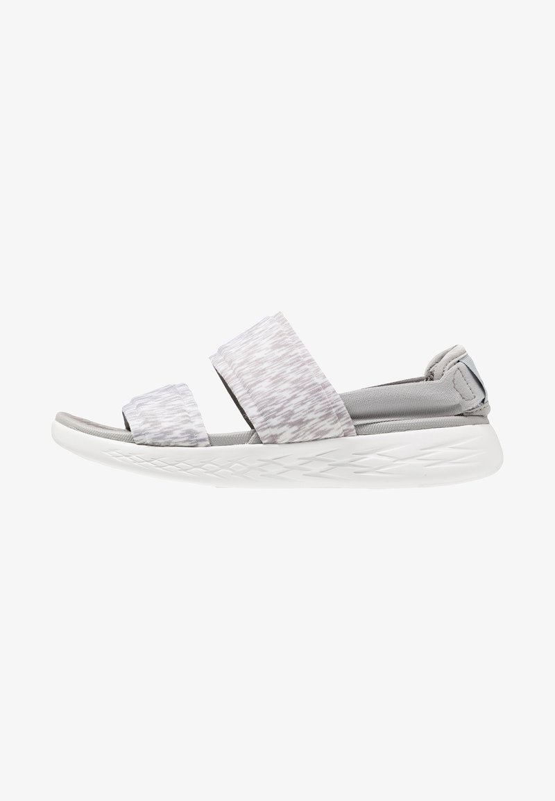Sandali open-toe grigio chiaro con due larghe cinghie in un motivo testurizzato, realizzati in materiale tessile morbido e con una suola bianca imbottita.