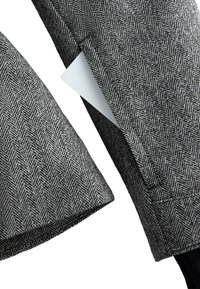 Šedá látka so vzorom rybej kosti, so štyrmi vreckami, pričom jedno vrecko zobrazuje bielu kartu. Viditeľné švy pozdĺž okrajov.