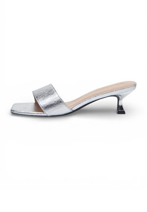 Mule argento con tacco kitten basso e ampia fascia frontale, profilo laterale visibile su sfondo bianco.