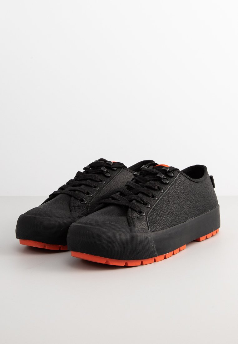 Sneaker nere in gomma con una parte superiore testurizzata, dotate di suole arancioni, punta rotonda e lacci a contrasto. Design semplice e funzionale.