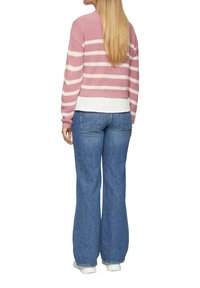 Rosa und weiß gestreifter Strickpullover mit einem cropped Design, kombiniert mit hellblauen Schlagjeans und weißen Turnschuhen. Rückansicht.