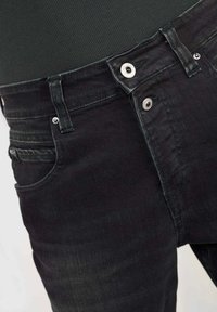 Zwarte denim jeans met een klassieke vijf-pocket ontwerp, zichtbare stiksels, metalen knoopsluiting en een lichte vervaging in de stoftextuur.