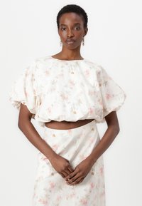 Set di crop top e gonna floreale in crema chiaro, con maniche a palloncino, delicati motivi rosa e beige, e una vita leggermente arricciata.