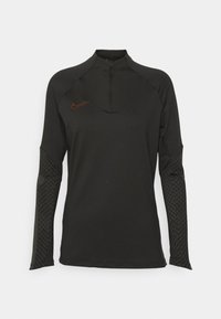 Schwarzes sportliches Langarmshirt mit einem Viertel-Reißverschluss, das ein texturiertes geometrisches Muster an den Ärmeln und das Nike-Logo in Orange auf der Brust aufweist.