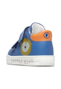 Sneaker blu per bambini con grafica di un leone sul lato, suola bianca, accento arancione sul tallone e chiusura con strap in Velcro. Testo: "Re della Giungla."