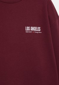 Sweatshirt bordeaux avec texte blanc indiquant "LOS ANGELES Honor Society Training Season" sur la zone gauche de la poitrine.
