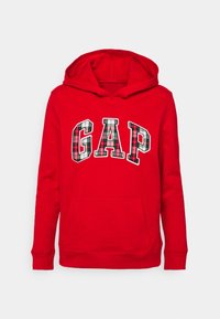 Sudadera roja con capucha que presenta un gran logo "GAP" en un patrón de cuadros, bolsillo frontal estilo canguro y puños y dobladillo acanalados. Textura de tela suave.