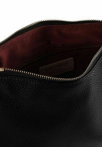 Borsetta in pelle nera con esterno texturizzato. Interno foderato in tessuto bordeaux, con chiusura a zip dorata e etichetta del marchio visibile all'interno.