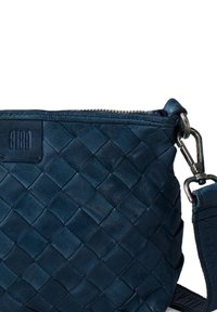 Marinblå vävd lädercrossbodyväska med dragkedjestängning, justerbar rem och präglad logotyp. Har en texturerad yta och silverfärgade detaljer.