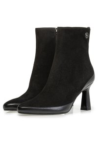 Botas de tobillo negras de ante con puntera afilada y un acento de cuero suave. Cuentan con un cierre con cremallera y un tacón alto y afinado.