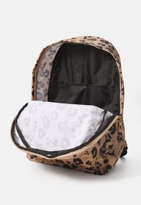Leopard print backpack in brown and black, featuring a spacious interior with a grey patterned lining and multiple interior pockets.