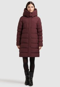 Bordoopunane tepitud sulejope kõrge kraega, horisontaalse triibulise mustriga, ees nupud ja üks rinnatasku. Kandmisega mustad põlveni ulatuvad saapad.