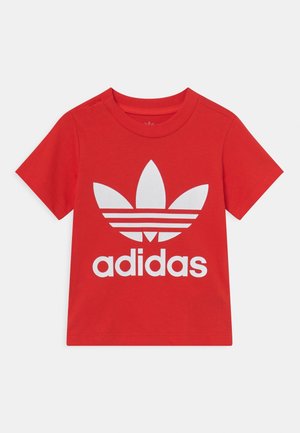 Czerwony t-shirt z krótkim rękawem z dużym białym logo Adidas trefoil oraz tekstem "adidas" wyśrodkowanym z przodu.
