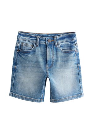Băiat stând și uitându-se în lateral, purtând un tricou alb simplu, pantaloni scurți din denim, șosete albe și adidași negri pe un fundal neutru.
