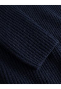 Mornarsko modra ribana tkanina z mehko teksturo, ki prikazuje posnetek rukava. Vzorec prikazuje izmenične navpične črte.