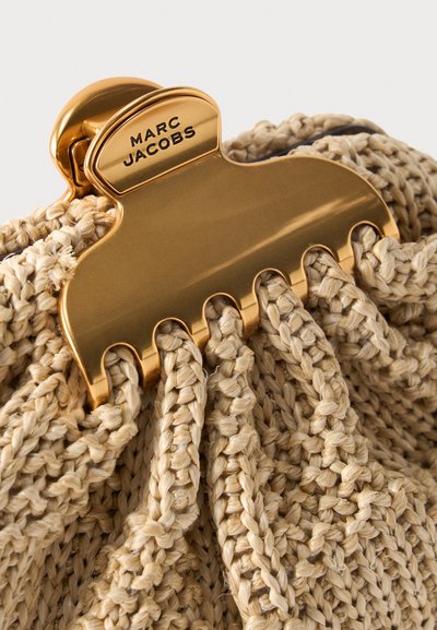 Χρυσό κλιπ για τα μαλλιά Marc Jacobs που συγκρατεί υφαντό μπεζ υλικό από ψάθα ή ύφασμα τσάντας.