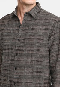 Camicia button-up di colore grigio scuro con un motivo a quadri strutturato. Presenta un colletto all'americana e bottoni neri, realizzata in un tessuto traspirante.