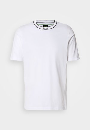 Balta īsām piedurknēm T-kreklā ar melnu un zaļu ribotu apļa kakla izgriezumu. Iezīmē smalku faktūru, bez rakstiem un ar slaidu piegriezumu.