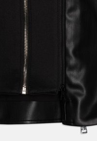 Czarna kurtka o gładkiej skórzanej powierzchni i tkaninowych panelach. Centralny srebrny zamek błyskawiczny, zdobiona połyskującymi detalami metalowymi.