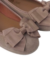 Bailarinas en ante beige con un detalle de lazo de cinta ribeteada y brillante en la puntera. Forma redondeada con una suela flexible y plana.