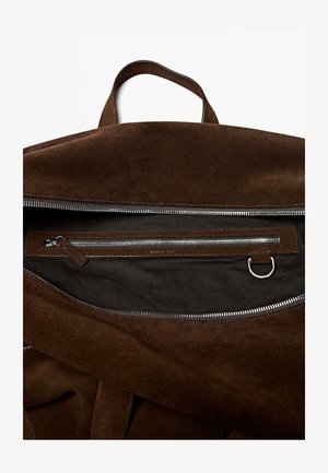 Borsa in suede marrone con forma solida; presenta un'ampia apertura con cerniera, tasca interna con zip e dettagli in pelle. Interno strutturato.