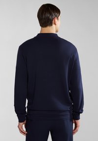 Navy long-sleeve polo shirt with a soft texture and a classic design, featuring a collar and ribbed cuffs, shown from the back.