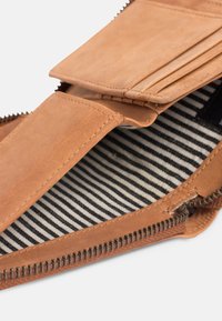 Leather wallet with a tan exterior, multiple card slots, and a striped fabric lining visible inside. Features a zippered closure.