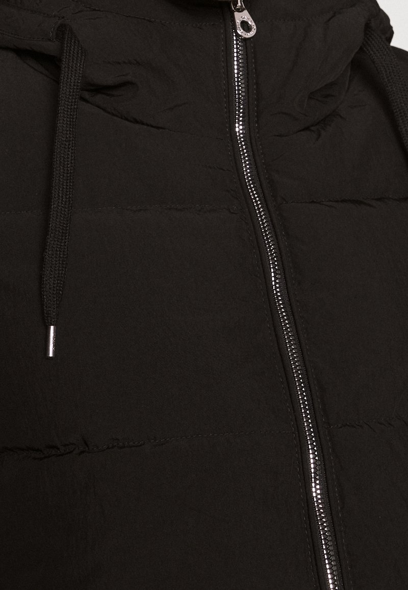 Schwarze gesteppte Jacke mit einem silbernen Reißverschluss und schwarzen Kordeln, die den oberen Oberkörperbereich und die Verschlussdetails zeigt.