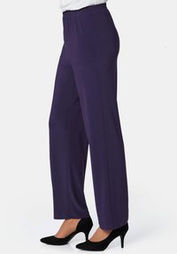 Lila Gummizug-Hosen mit einem geraden Bein Design, aus weichem, dehnbarem Material, kombiniert mit schwarzen High Heels.