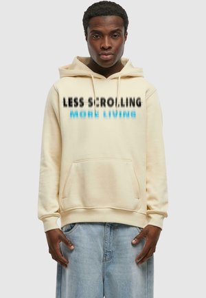 Cream-colored hoodie with front pocket. Features black and blue text: "LESS SCROLLING" and "MORE LIVING." Cotton blend fabric, relaxed fit.
