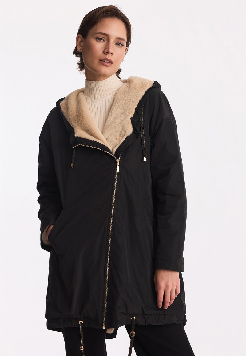 Czarna parka z futrzanym wykończeniem i kapturem, z zamkiem z przodu, sznurkami w talii oraz bocznymi kieszeniami.