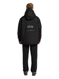 Person mit Dutt, die eine schwarze Kapuzenjacke und Hose trägt, steht mit dem Rücken zur Kamera, mit dem Schriftzug "ATW" und Logo auf der Rückseite der Jacke.