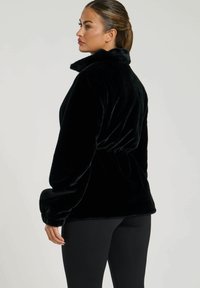 Pullover in fleece nero con colletto alto, vita stretta e maniche lunghe. Texture morbida con una finitura liscia, progettato per comfort e calore.