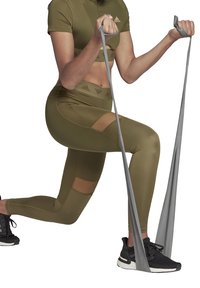 Atletische outfit in olijfgroen, bestaande uit een strakke crop top en high-waisted leggings met mesh uitsparingen. De greep van de weerstandsband is grijs.