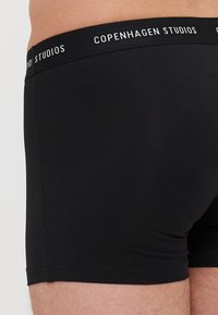 Sorte bomullsboksershorts med en tettsittende design. Elastisk livlinje med trykt "Copenhagen Studios"-logo. Glatt tekstur.